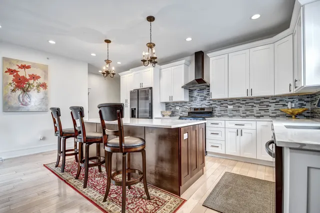 a kitchen with stainless steel appliances kitchen island granite countertop a table chairs sink and cabinets