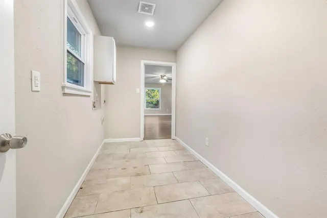 a view of an empty room with wooden floor and window