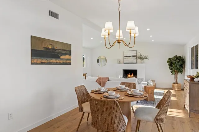 a dining room with wooden floor a chandelier a wooden table and chairs