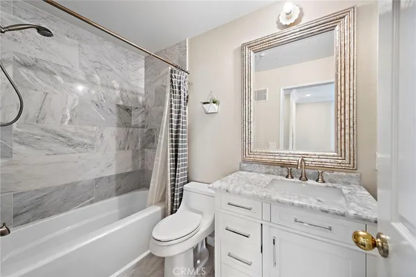 a bathroom with a granite countertop sink a toilet and shower