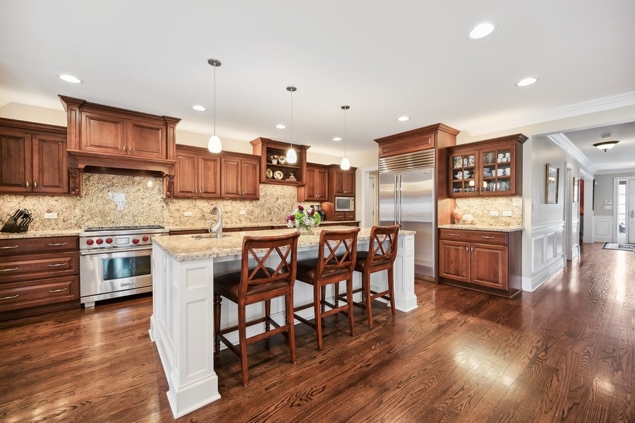 632 Chatham Road Glenview, IL 60025 - Photo 11 of 52 a kitchen with stainless steel appliances kitchen island granite countertop wooden floors cabinets and dining table