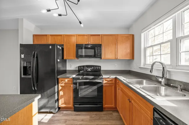 a kitchen with granite countertop a sink stainless steel appliances and window