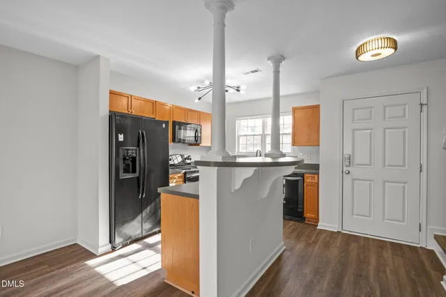 a kitchen with stainless steel appliances granite countertop a refrigerator a sink dishwasher a stove and white countertops with wooden floor