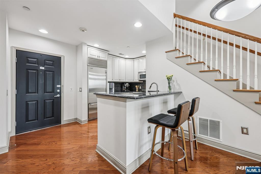 7400 River Road, Unit 409 North Bergen, NJ 07047 - Photo 7 of 30 a kitchen with white cabinets and stainless steel appliances
