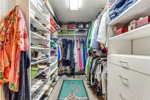 a view of walk in closet with clothes and shoes