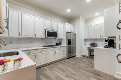 a kitchen with stainless steel appliances granite countertop a stove top oven a sink dishwasher and a refrigerator with wooden floor