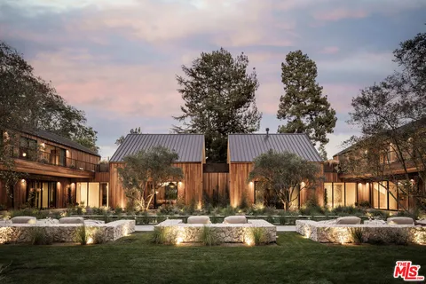 a front view of a building with garden and trees