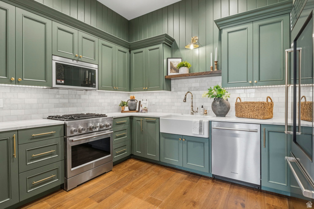 115 East Hidden Ridge Lane, Unit 42 Mapleton, UT 84664 - Photo 59 of 103 Kitchen featuring wood-finish flooring, shaker-style cabinetry with gold-tone hardware, a farmhouse-style sink, stainless steel appliances, and a subway tile backsplash