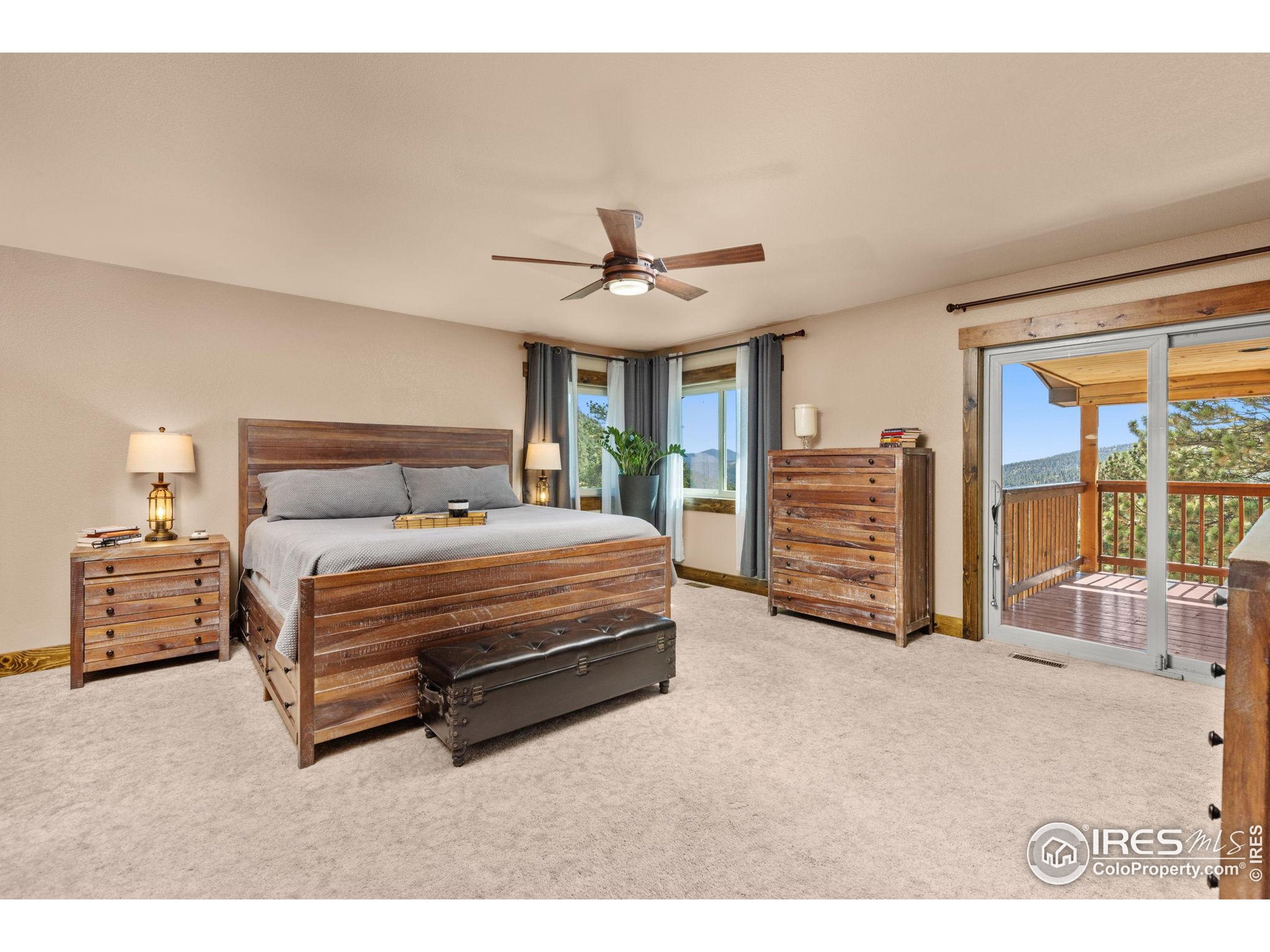 681 Bitterroot Gulch Road Loveland, CO 80537 - Photo 19 of 47 a spacious bedroom with a bed a dresser and a chandelier