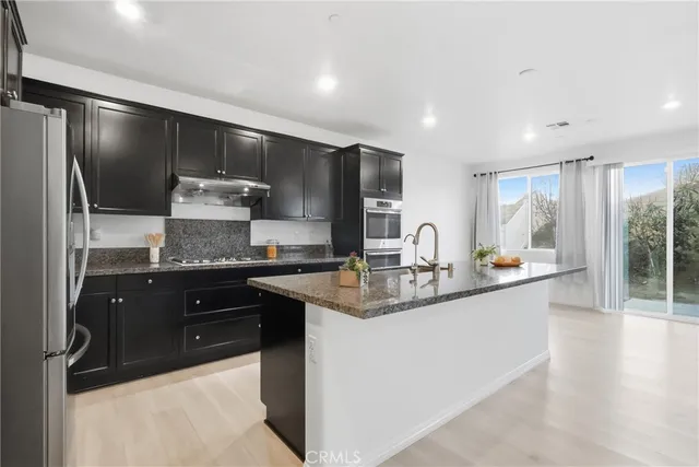 a kitchen with stainless steel appliances granite countertop a sink stove and refrigerator