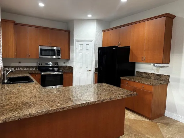 a kitchen with stainless steel appliances granite countertop a refrigerator a stove a sink and a microwave