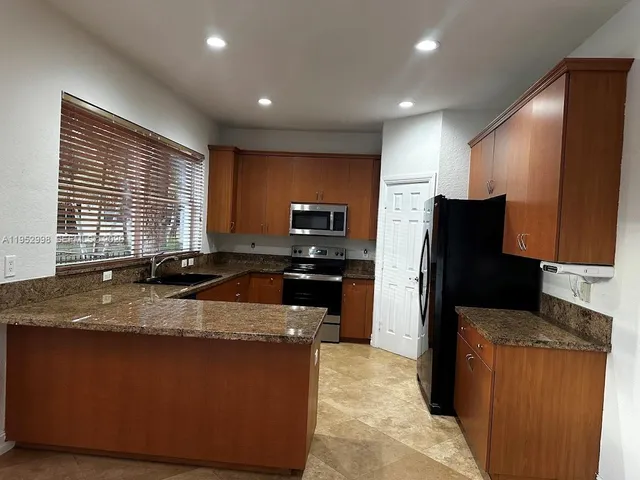 a kitchen with stainless steel appliances granite countertop a refrigerator a stove a sink dishwasher and a refrigerator