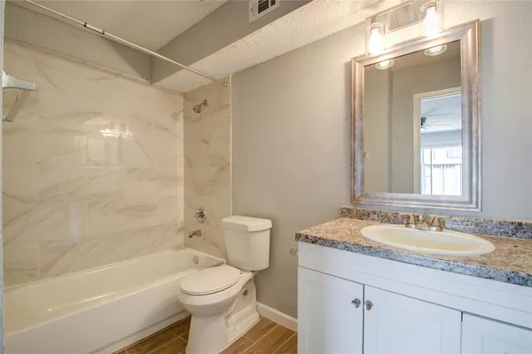 a bathroom with a granite countertop sink a toilet and shower