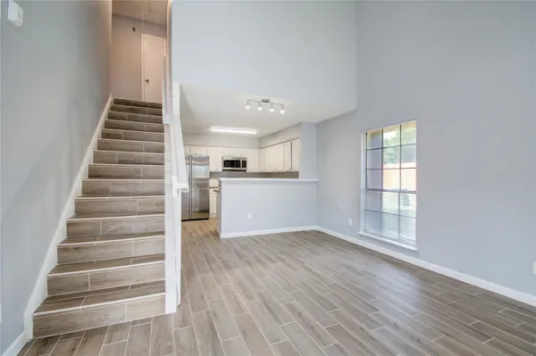 a view of an empty room with wooden floor and stairs