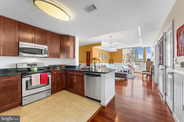 a kitchen with stainless steel appliances granite countertop a stove a sink dishwasher and a refrigerator with wooden floor