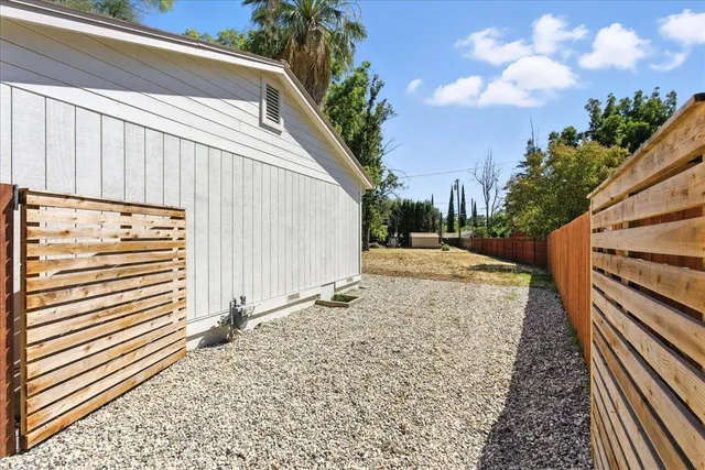 a backyard of a house with large trees and wooden fence
