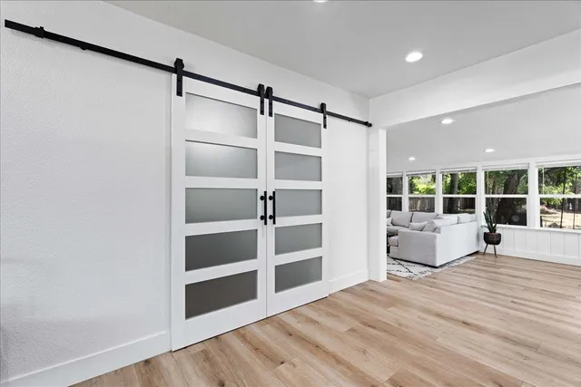 a view of an empty room with wooden floor and windows