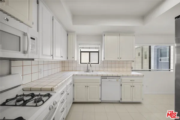 a kitchen with cabinets appliances a sink and a window