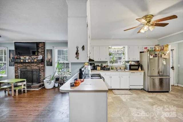 a kitchen with stainless steel appliances granite countertop a refrigerator a stove a sink and white cabinets