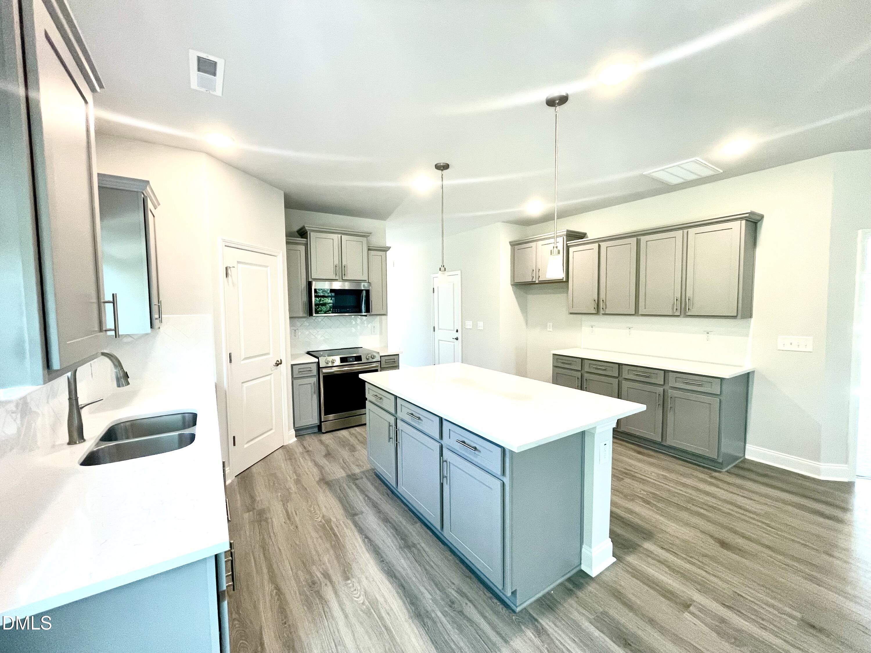 39 Deep Blue Trail Middlesex, NC 27557 - Photo 7 of 37 a large kitchen with a stove a sink dishwasher and a refrigerator with wooden floor
