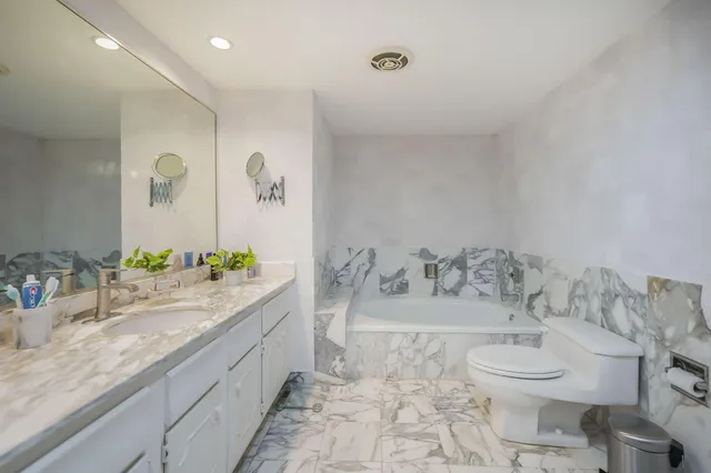 a bathroom with a granite countertop sink mirror vanity and toilet