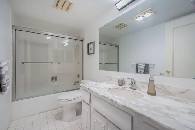 a bathroom with a granite countertop sink a toilet and shower