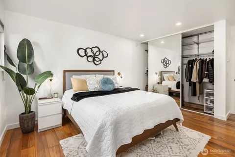 a bedroom with a bed and a potted plant on the dresser