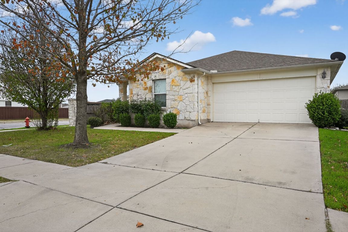 Ranch-style home with stone siding, concrete driveway, a garage, and a shingled roof