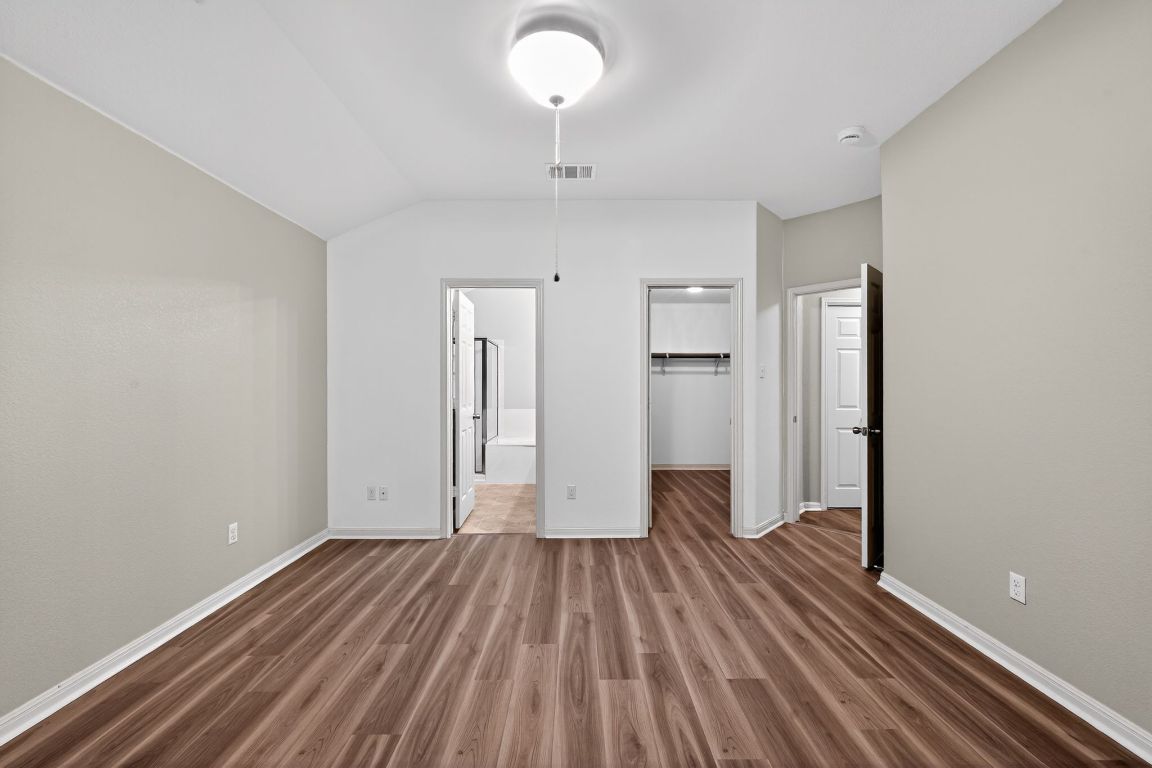 13237 Pine Needle Street Manor, TX 78653 - Photo 11 of 16 bedroom featuring a spacious closet, wood finished floors, lofted ceiling, and connected bathroom