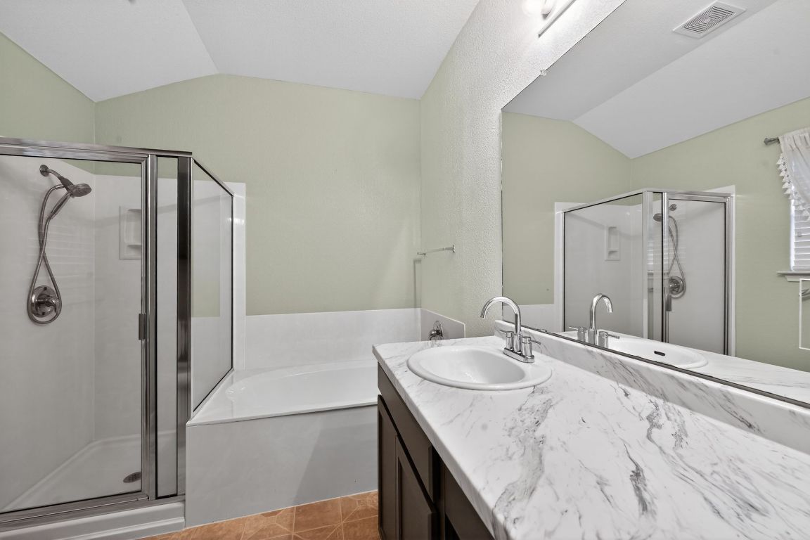 13237 Pine Needle Street Manor, TX 78653 - Photo 13 of 16 Full bath with lofted ceiling, vanity, a bath, a shower stall, and light tile patterned flooring