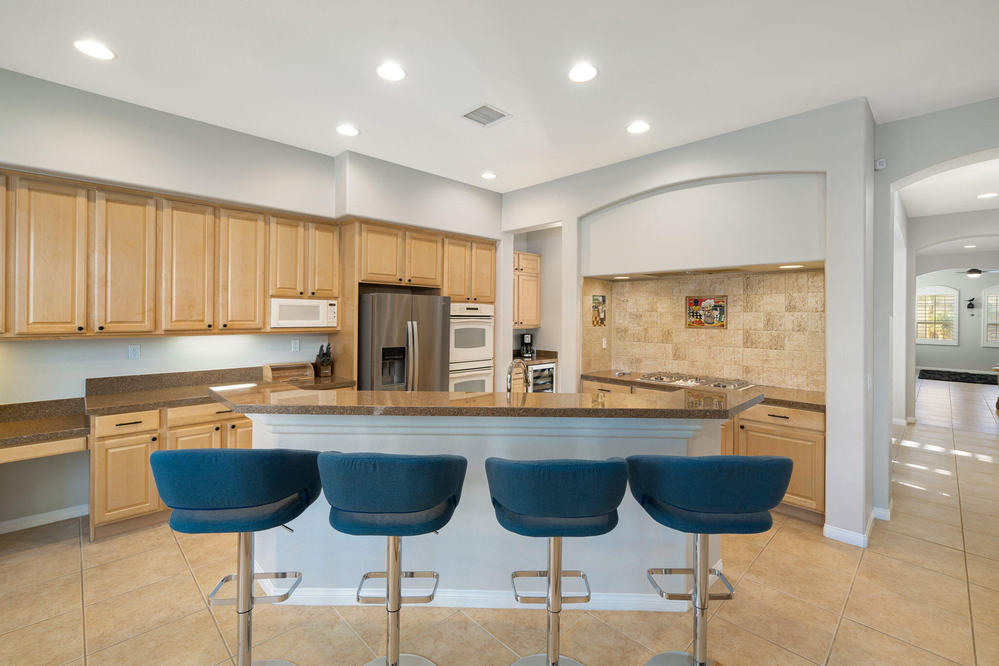68 Via Del Pienza Rancho Mirage, CA 92270 - Photo 24 of 38 a kitchen with stainless steel appliances granite countertop a stove a sink a island with chairs and wooden cabinets