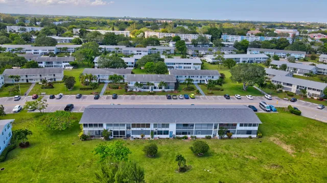 a patio with a table and chairs under an umbrella with palm trees