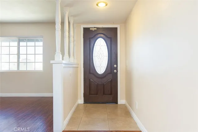 an entryway with wooden floor mirror and a window