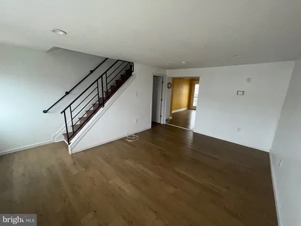 a view of an empty room with wooden floor and stairs