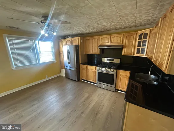 a kitchen with granite countertop a stove a refrigerator and wooden floor