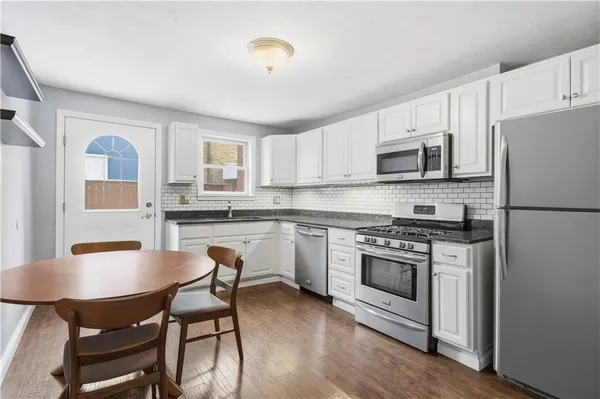 a kitchen with stainless steel appliances granite countertop a stove a sink dishwasher and a microwave oven with wooden cabinets