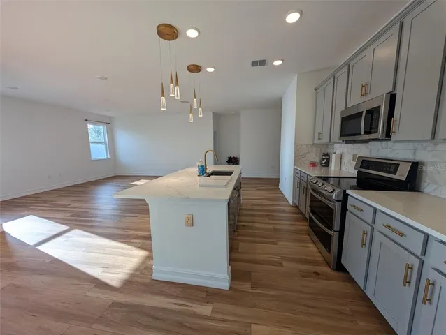 a kitchen with stainless steel appliances kitchen island granite countertop a stove a sink and a refrigerator