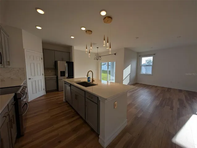 a large kitchen with stainless steel appliances granite countertop a lot of counter space and wooden floor