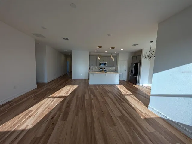 a large kitchen with kitchen island a stove a sink dishwasher and a refrigerator with wooden floor