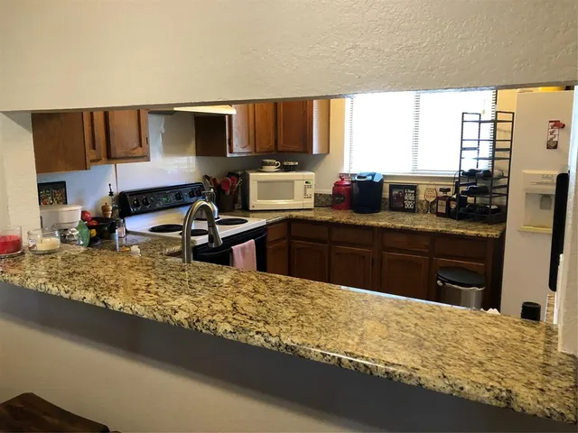 a kitchen with kitchen island granite countertop a sink appliances and cabinets