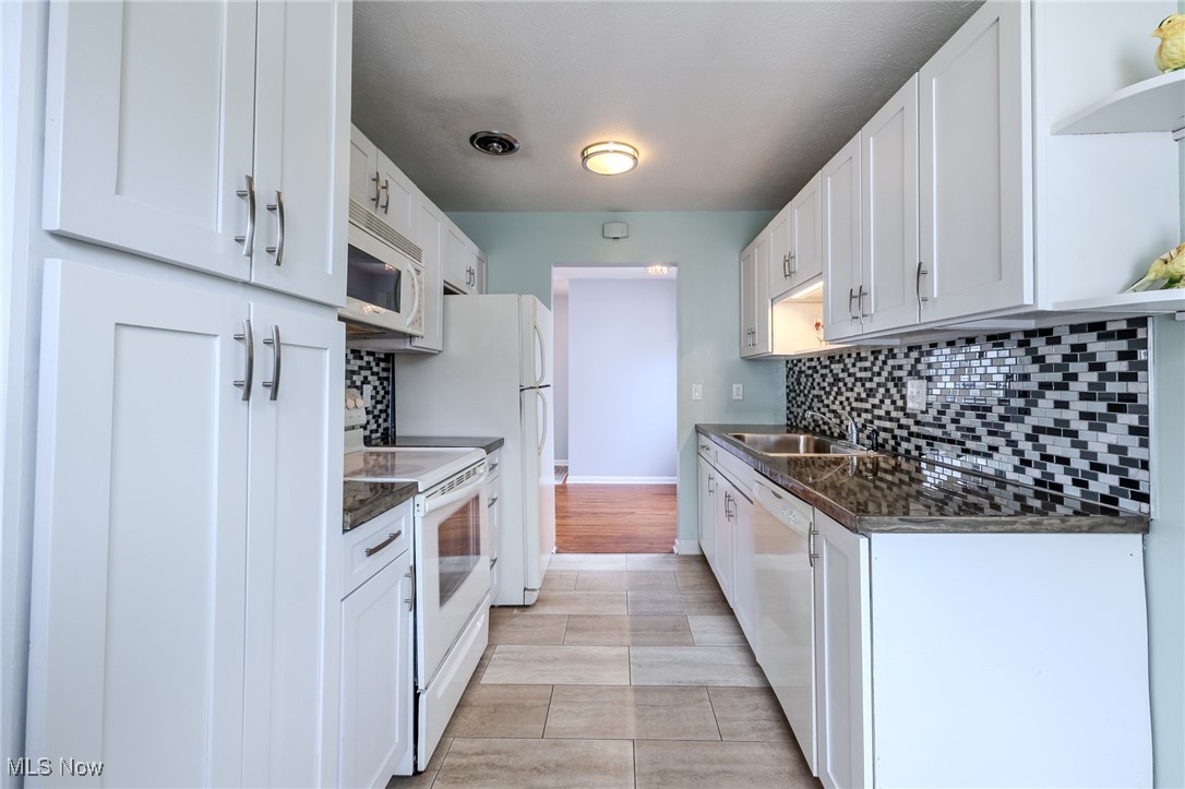29971 Regent Road Wickliffe, OH 44092 - Photo 6 of 39 Kitchen with white appliances, dark countertops, open shelves, and decorative backsplash