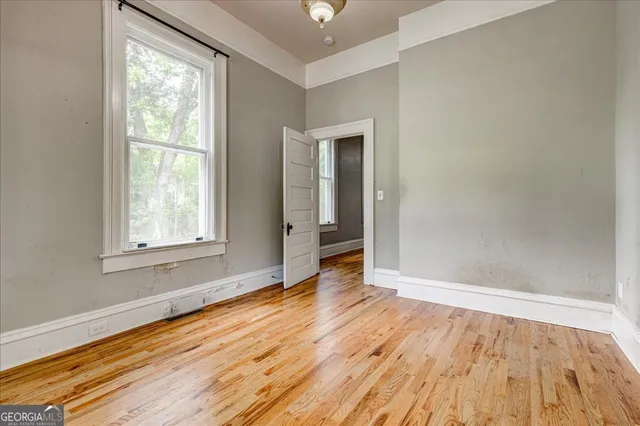 an empty room with wooden floor and windows