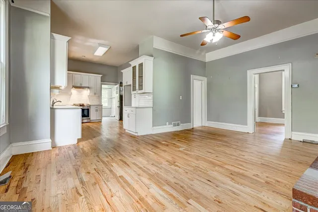 a view of empty room with wooden floor and kitchen view