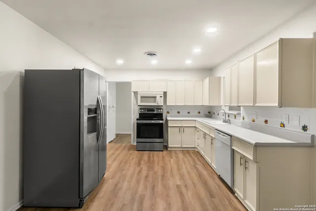 a large kitchen with a center island wooden floor stainless steel appliances and cabinets