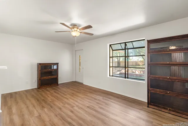 a view of empty room with wooden floor and fan