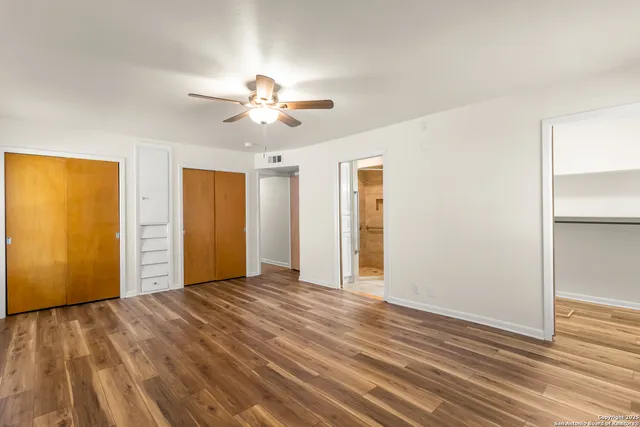 a view of empty room with wooden floor and fan