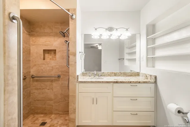 a bathroom with a granite countertop sink a mirror and a shower
