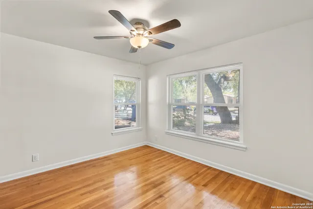 a view of an empty room with a window and wooden floor