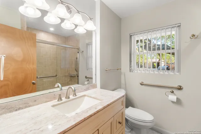 a bathroom with a granite countertop sink mirror vanity and toilet