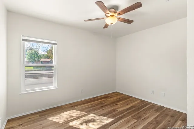 a view of a room with wooden floor and a ceiling fan